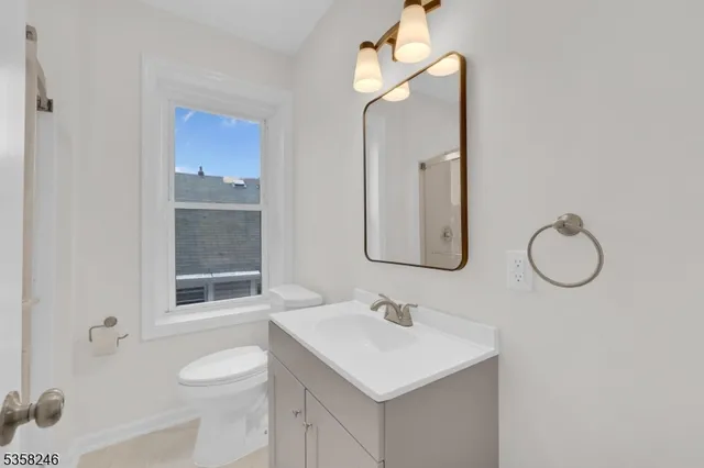 a bathroom with a sink vanity granite toilet and a mirror