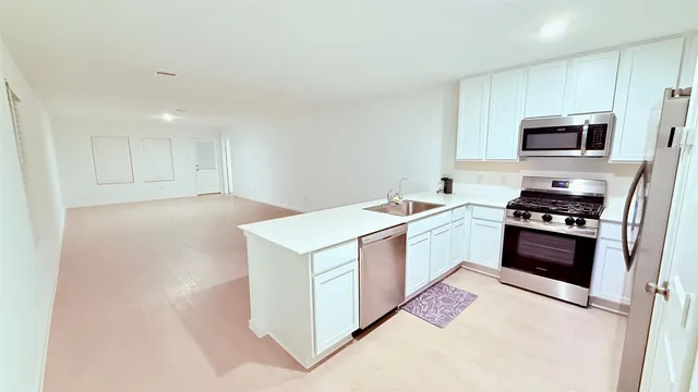 a kitchen with a refrigerator a sink a stove a microwave a counter top space and cabinets