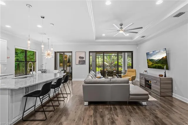 a living room with furniture a large window and wooden floor