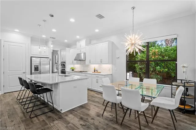 a kitchen with a dining table chairs and white cabinets