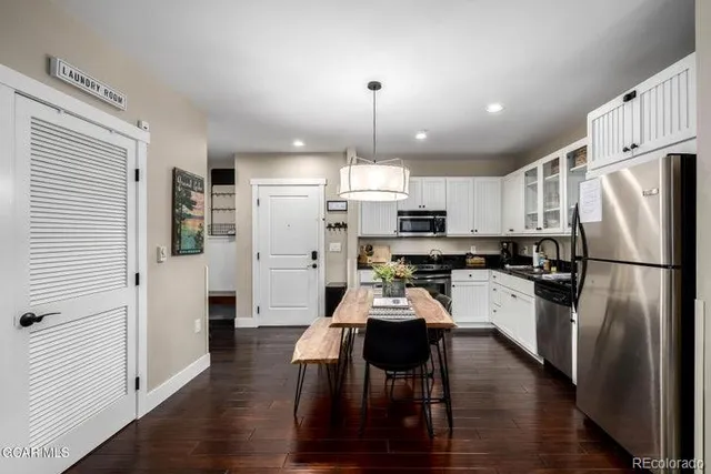 a kitchen with stainless steel appliances a refrigerator a stove top oven a sink dishwasher and white cabinets with wooden floor