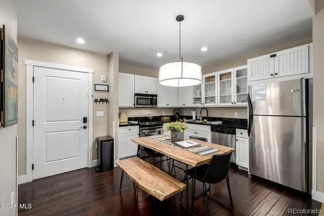 a kitchen with a refrigerator a stove a sink dishwasher and a dining table with wooden floor