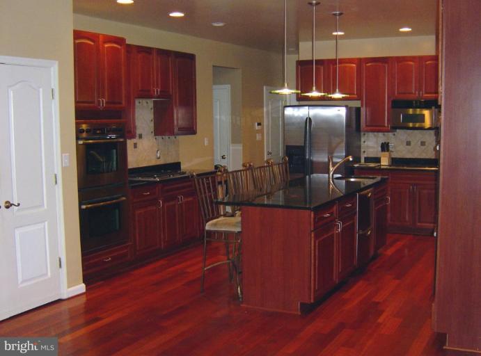 622 Church Road Reisterstown, MD 21136 - Photo 9 of 21 a kitchen with stainless steel appliances kitchen island granite countertop a stove a refrigerator a sink and dishwasher with wooden floor