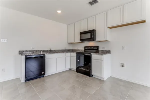 a kitchen with granite countertop a stove top oven and cabinets