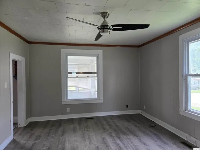 a view of an empty room with a window and wooden floor