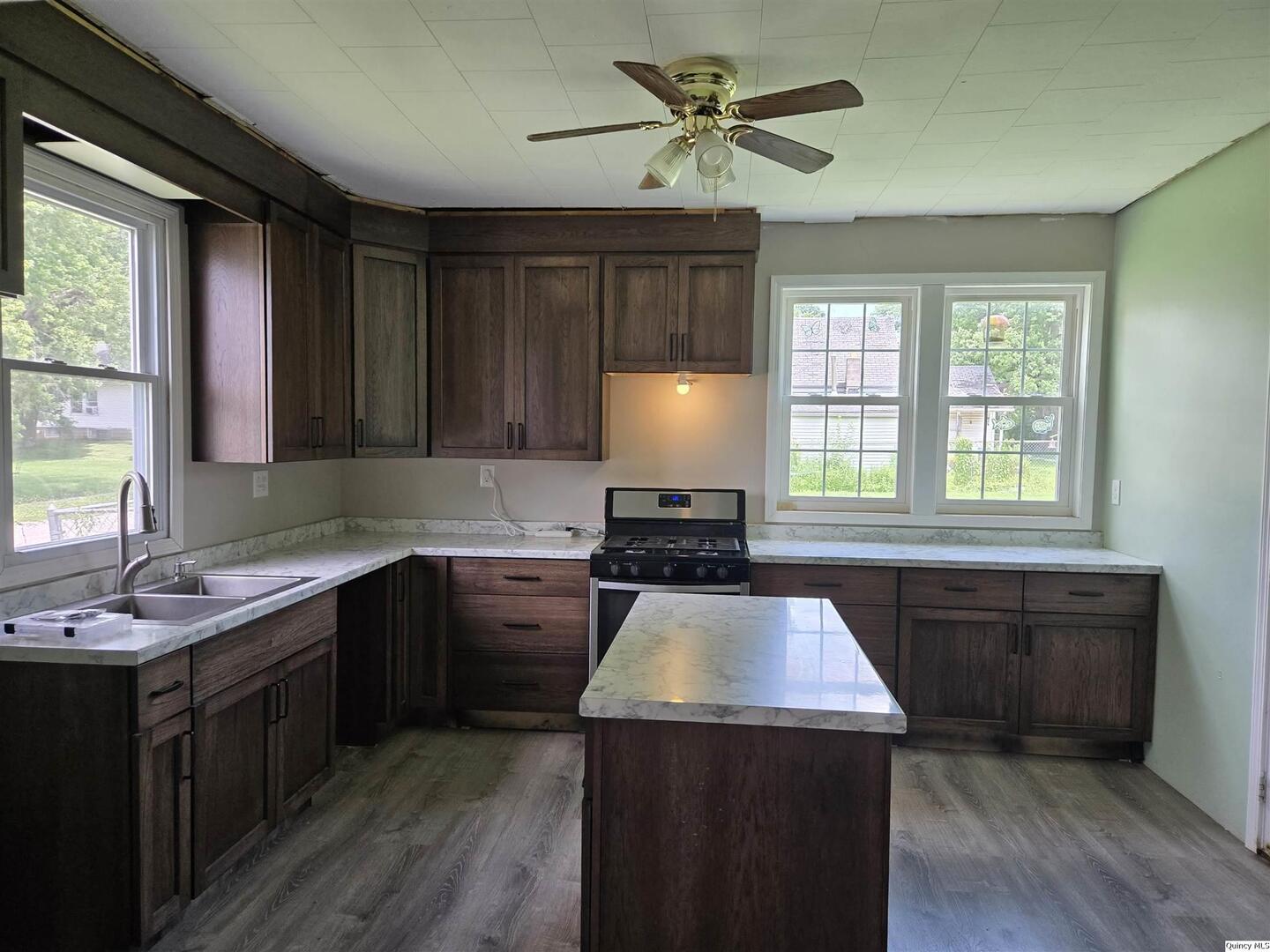 112 North Walnut Street Versailles, IL 62378 - Photo 8 of 18 a kitchen with a stove a sink a window and wooden floor