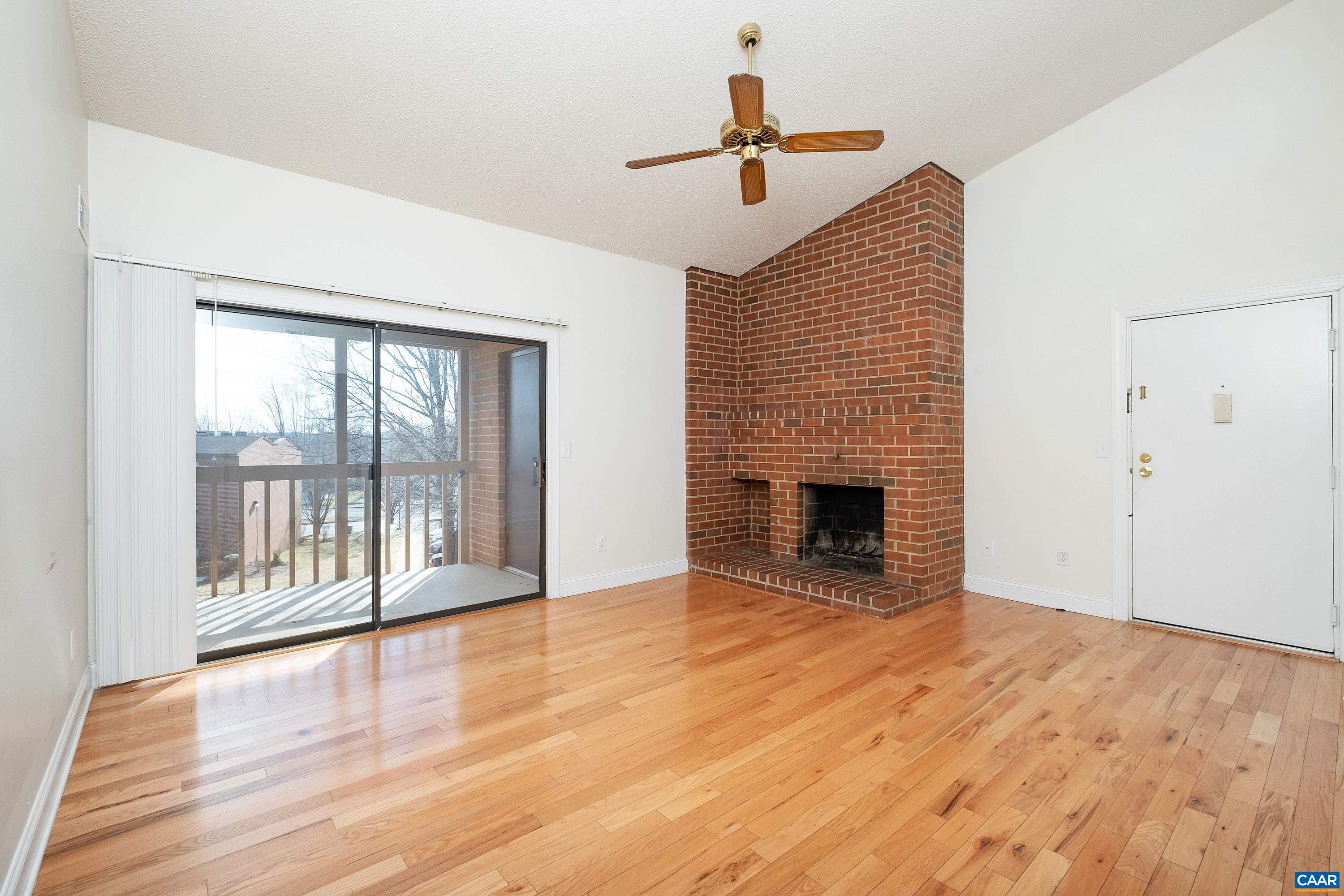 a view of an empty room with a fireplace and wooden floor