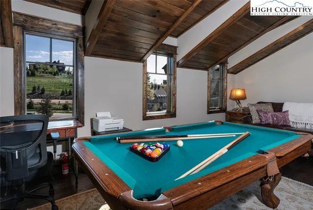 a room with furniture pool table kitchen view and a window