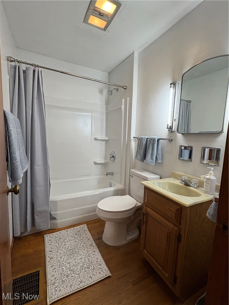 9801 Clay Pike Road Byesville, OH 43723 - Photo 17 of 27 Bathroom featuring visible vents, toilet, shower / tub combo with curtain, vanity, and wood finished floors