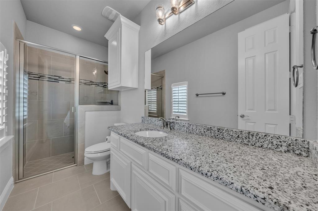 1060 Waters Edge Court Oak Point, TX 75068 - Photo 16 of 40 a bathroom with a granite countertop sink a toilet and shower