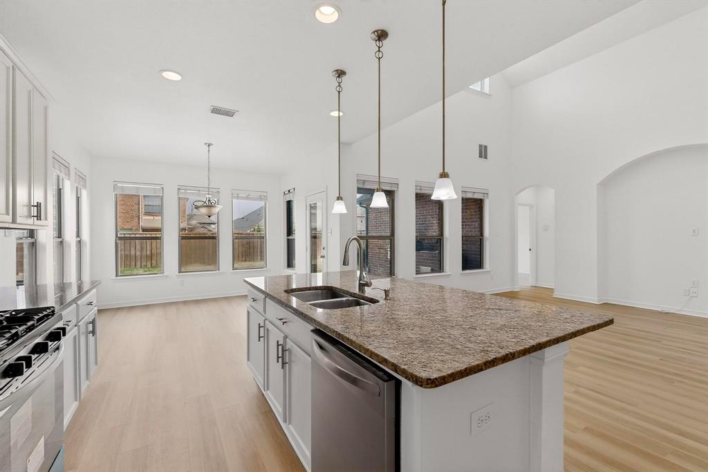 174 Hampton Drive Fate, TX 75087 - Photo 7 of 40 a kitchen with stainless steel appliances granite countertop a stove and kitchen island