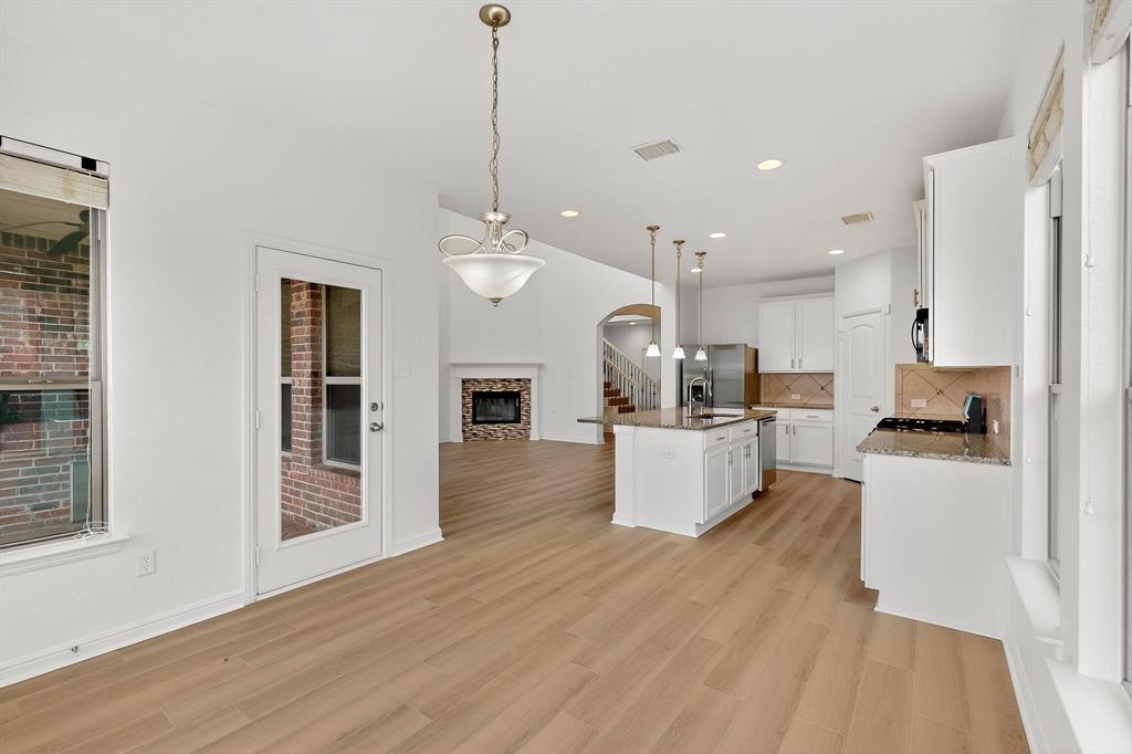 174 Hampton Drive Fate, TX 75087 - Photo 10 of 40 a large kitchen with kitchen island a stove a sink a refrigerator and white cabinets with wooden floor
