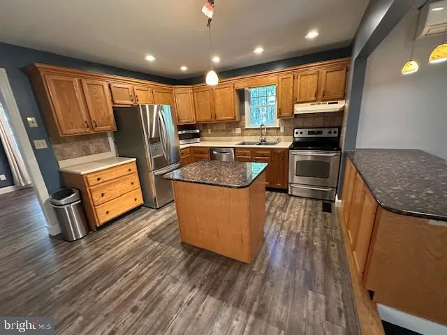 a kitchen that has a sink stainless steel appliances a window and a counter top space