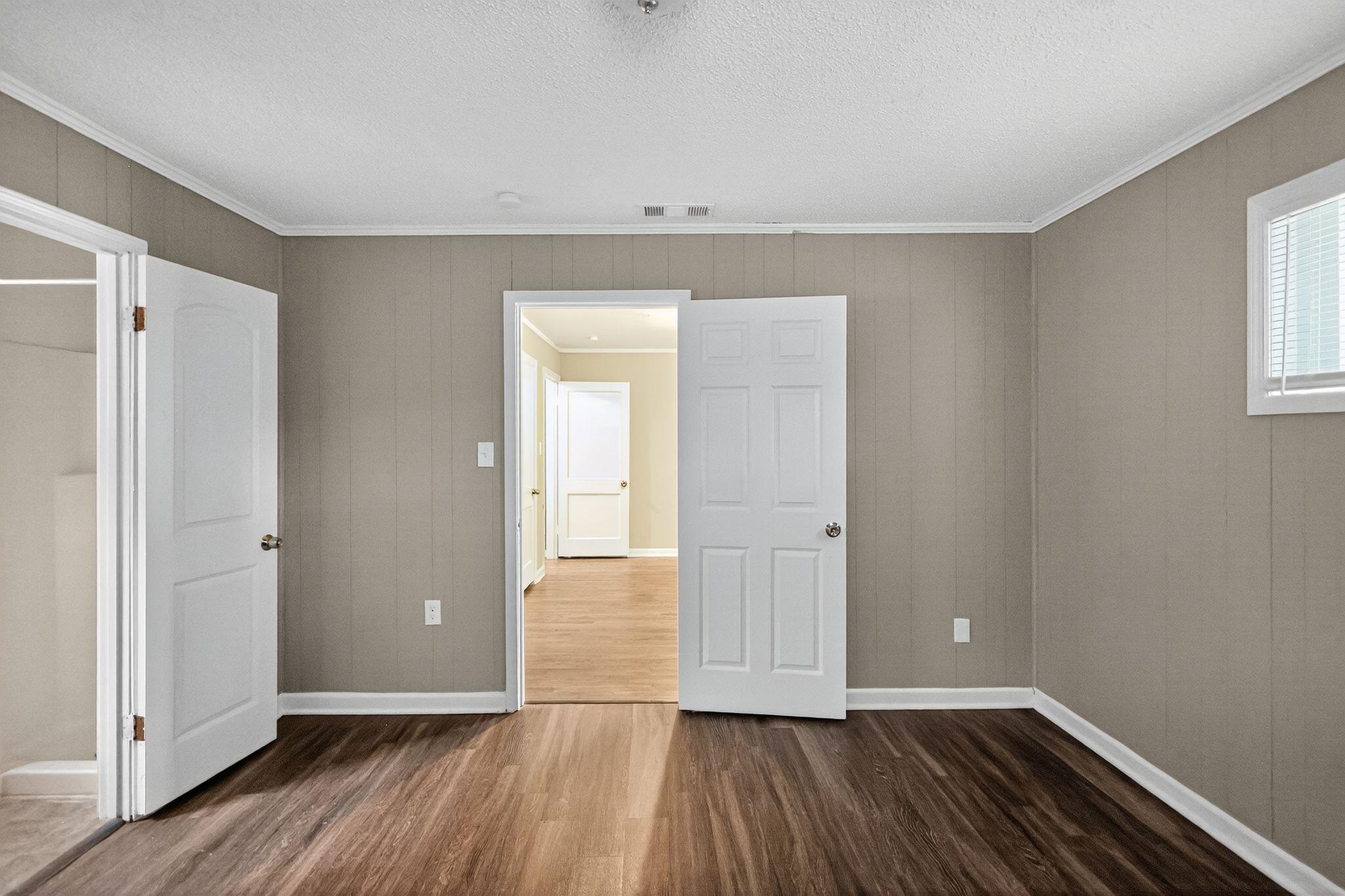 1563 Flamingo Road Memphis, TN 38117 - Photo 15 of 33 Unfurnished bedroom with dark wood-style floors, crown molding, wood walls, and a textured ceiling
