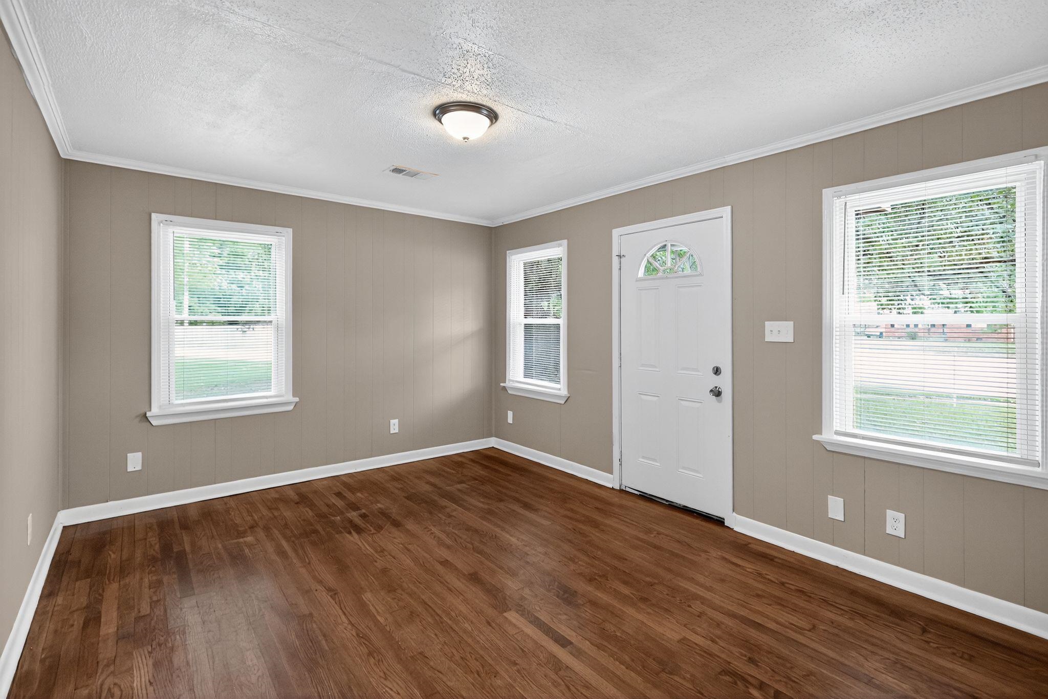 1563 Flamingo Road Memphis, TN 38117 - Photo 20 of 33 Foyer entrance with healthy amount of natural light, ornamental molding, a textured ceiling, dark wood finished floors, and wood walls