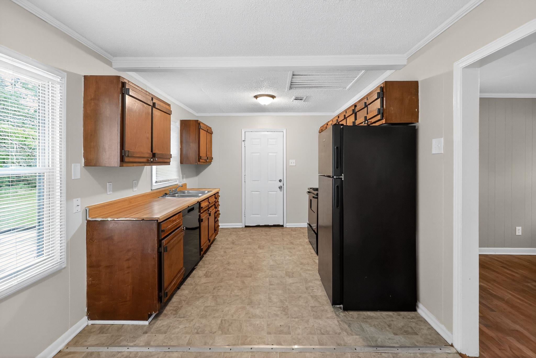 1563 Flamingo Road Memphis, TN 38117 - Photo 3 of 33 Kitchen featuring black appliances, crown molding, light countertops, a textured ceiling, and brown cabinets