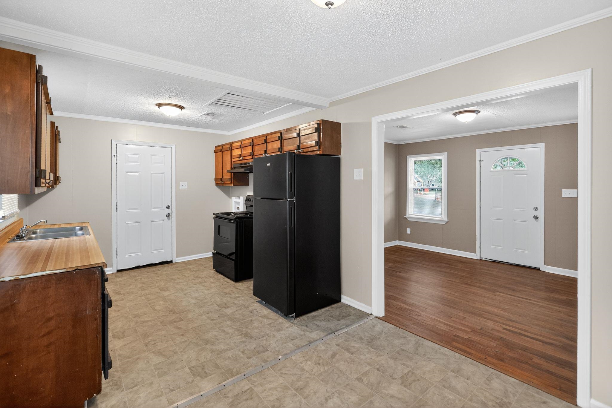 1563 Flamingo Road Memphis, TN 38117 - Photo 7 of 33 Kitchen with crown molding, black appliances, a textured ceiling, brown cabinetry, and light countertops