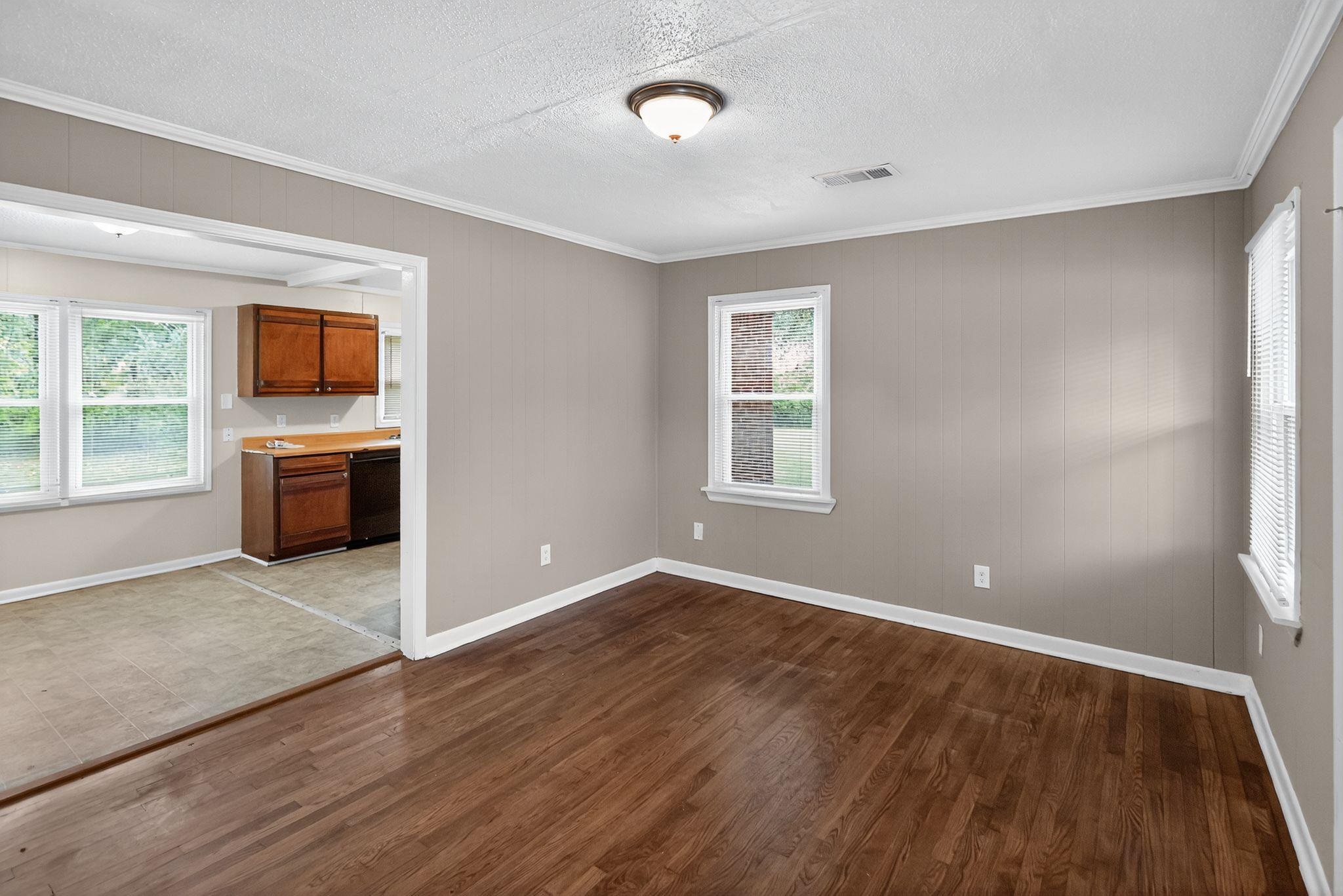 1563 Flamingo Road Memphis, TN 38117 - Photo 8 of 33 Unfurnished living room with healthy amount of natural light, crown molding, dark wood finished floors, wooden walls, and a textured ceiling