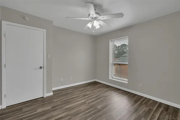 a view of an empty room with a window and wooden floor