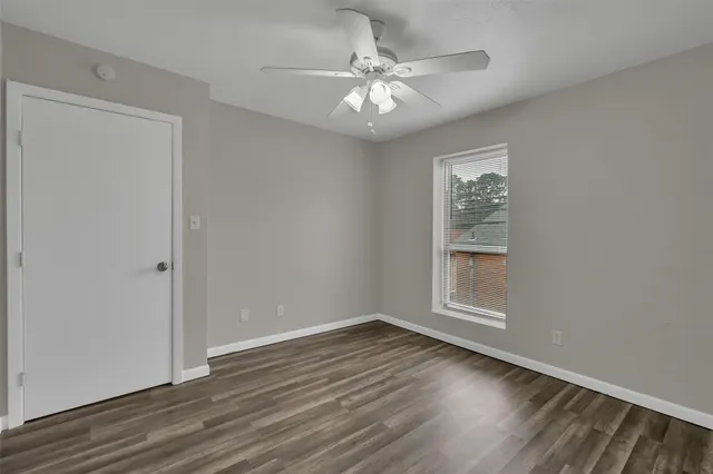 a view of an empty room with a window and wooden floor
