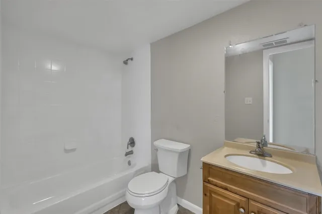 a bathroom with a granite countertop sink toilet mirror vanity and bathtub