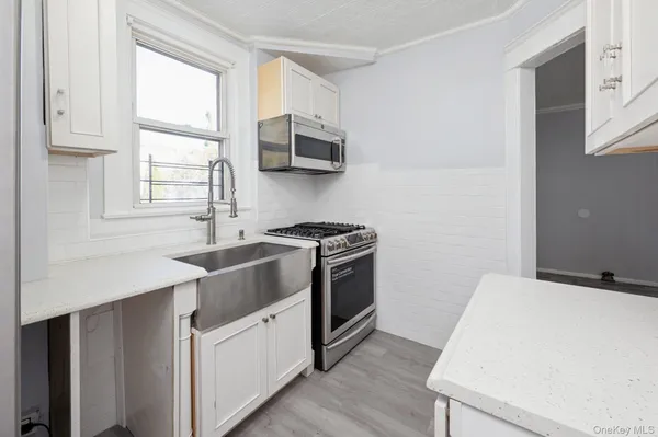 a kitchen with stainless steel appliances white cabinets and wooden floor