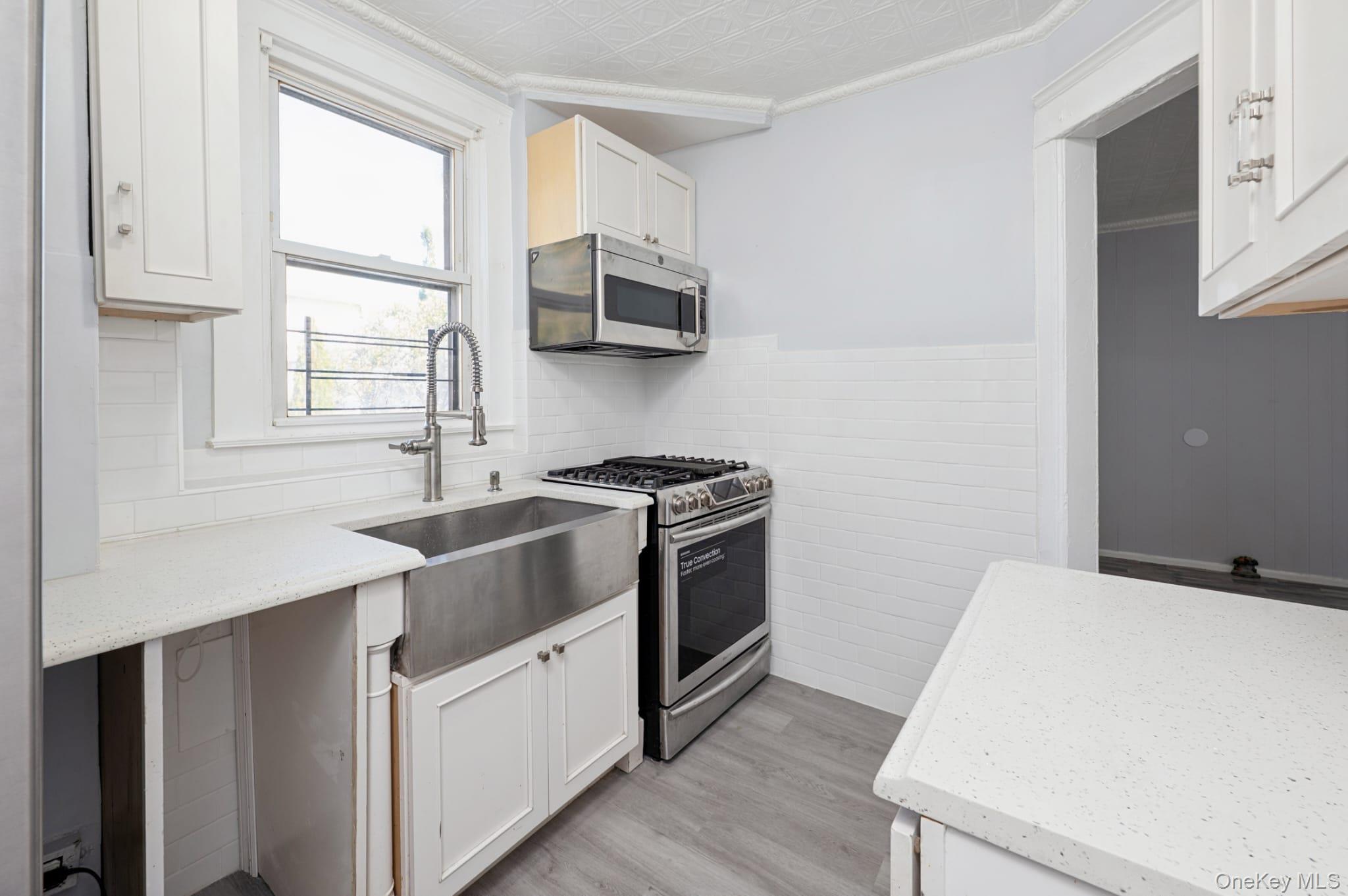 611 St Lawrence Avenue, Unit 1 Bronx, NY 10473 - Photo 9 of 20 a kitchen with stainless steel appliances white cabinets and wooden floor