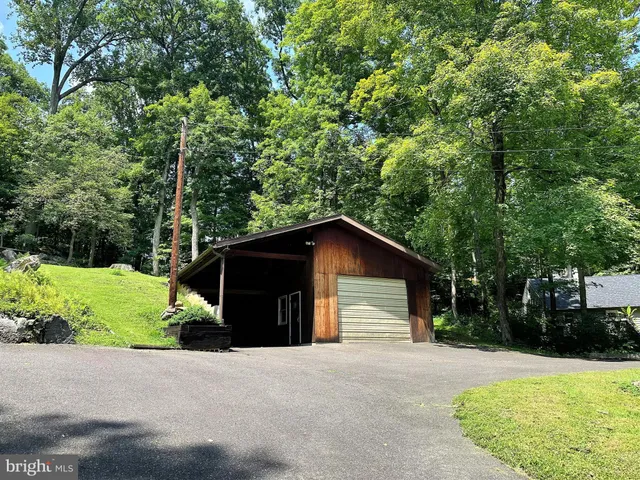 a view of a wooden house with a yard and large trees