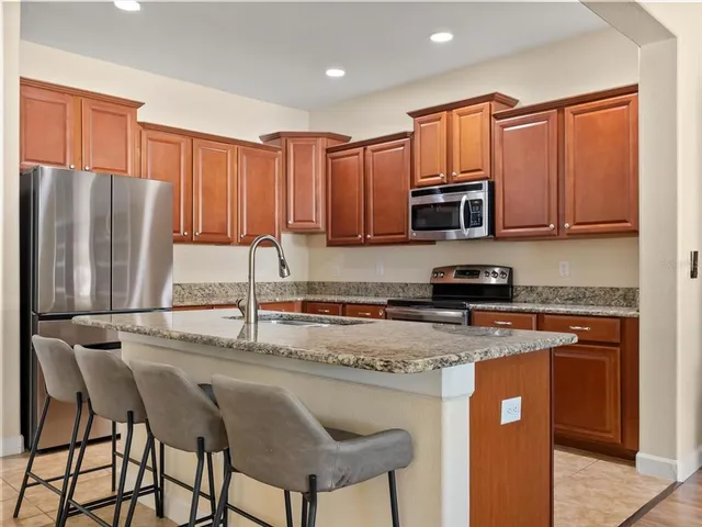 a kitchen with stainless steel appliances granite countertop a stove a sink refrigerator and a microwave