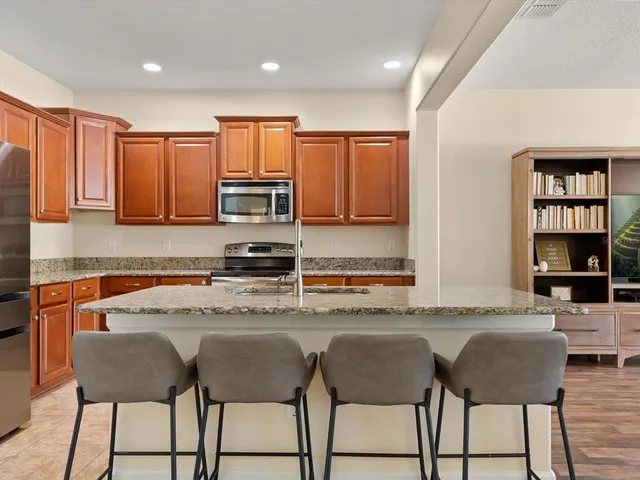 a kitchen with stainless steel appliances granite countertop a table chairs sink and cabinets