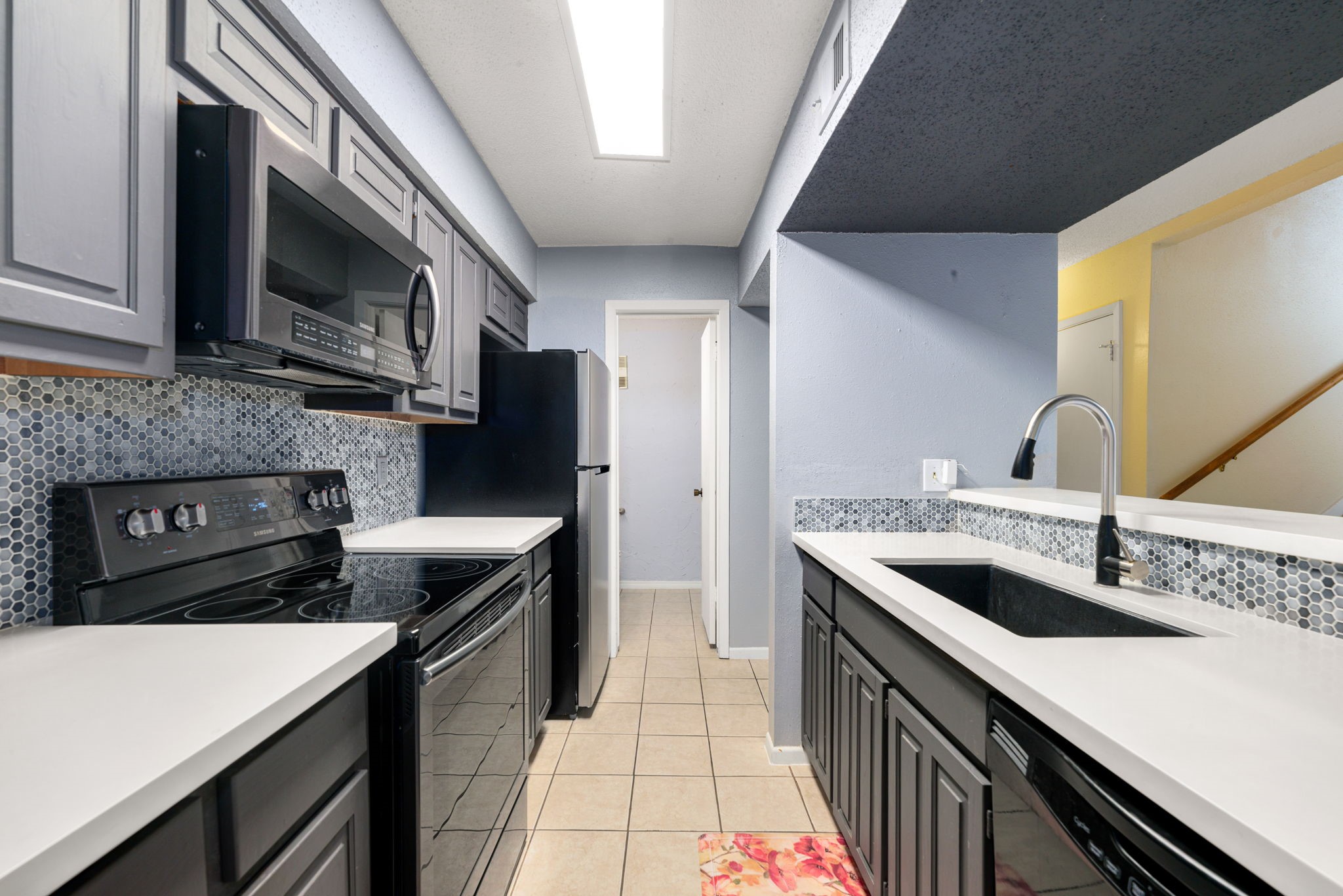 3200 South Gessner Road, Unit 228 Houston, TX 77063 - Photo 8 of 18 The updated kitchen features gray cabinetry, quartz countertops, a mosaic tile backsplash, black stainless steel appliances, an undermount sink with a modern faucet, and tile flooring, a functional and stylish space ready for any home chef!