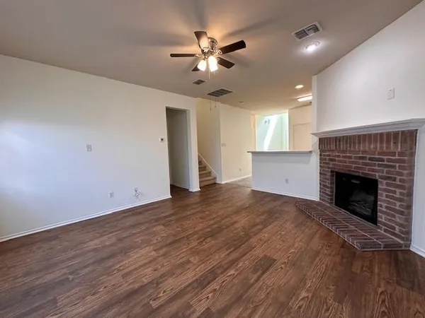 a view of an empty room with a fireplace and a ceiling fan
