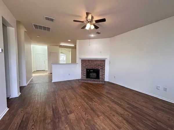 a view of an empty room with wooden floor and a fireplace