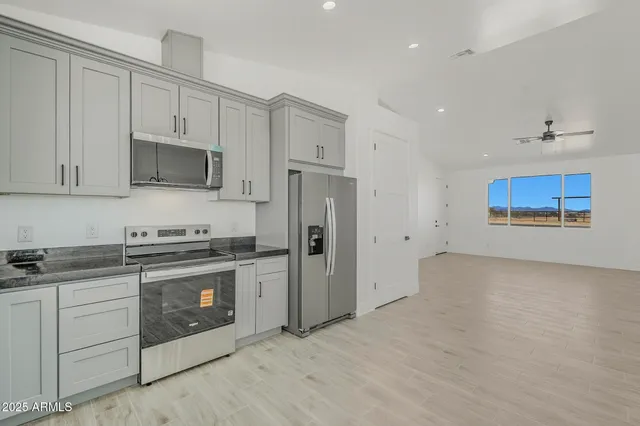 a large kitchen with stainless steel appliances kitchen island granite countertop a refrigerator a sink a stove and white cabinets