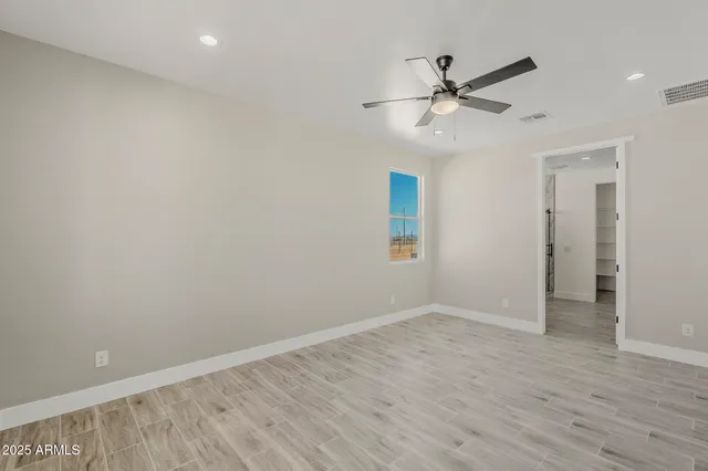 an empty room with wooden floor closet and fan