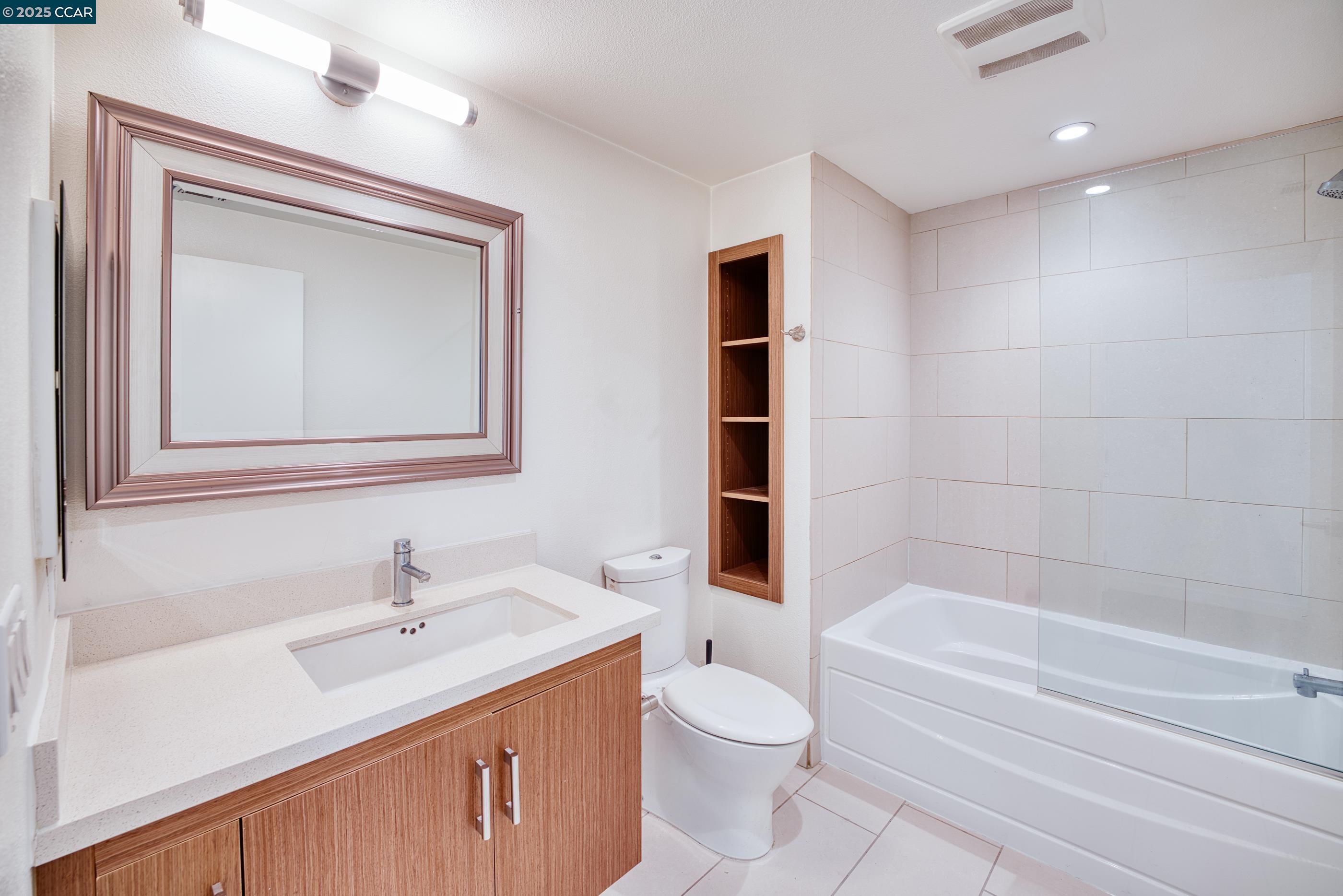 2655 Bush Street, Unit 110 San Francisco, CA 94115 - Photo 22 of 52 a bathroom with a toilet a sink a mirror a bathtub and vanity
