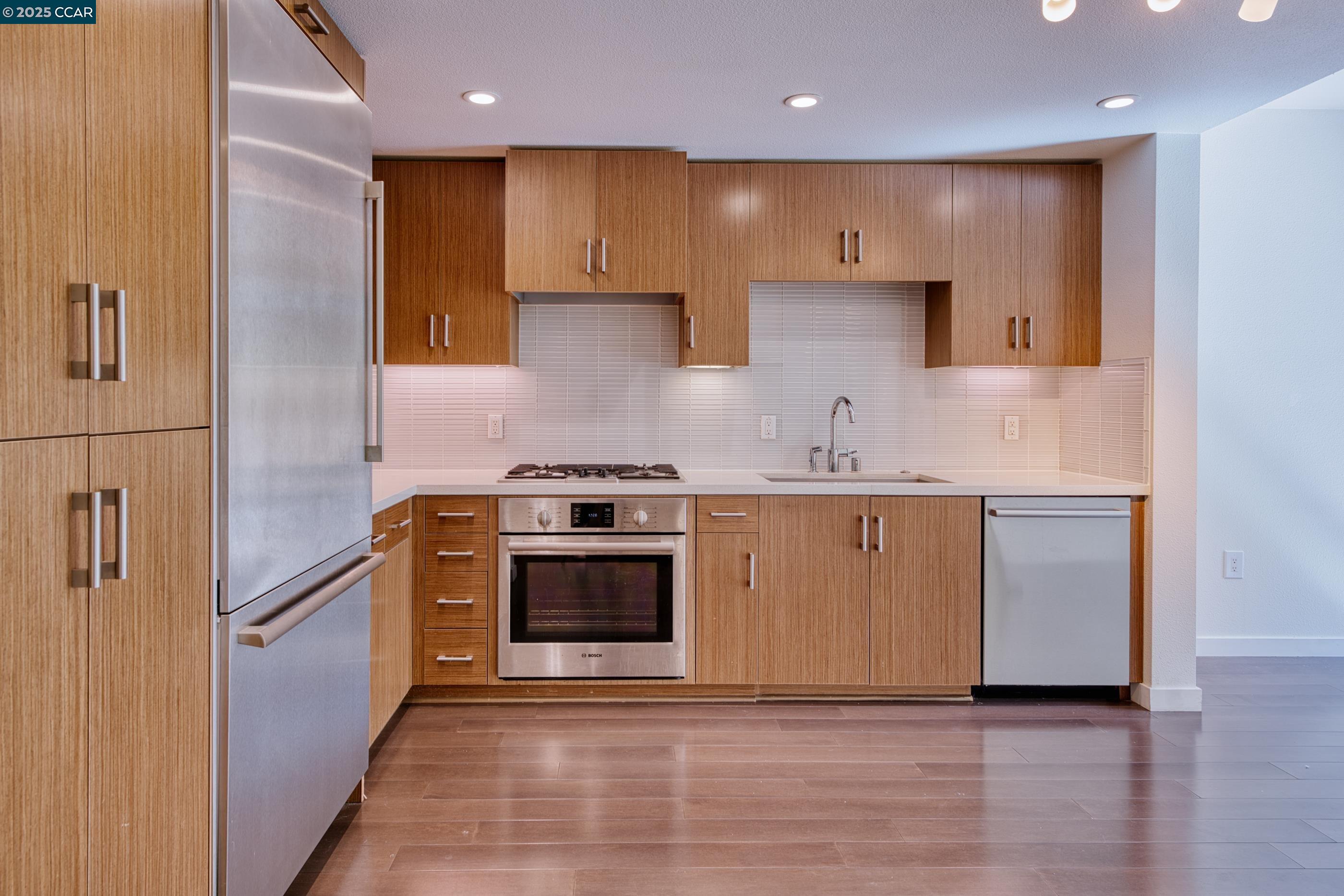 2655 Bush Street, Unit 110 San Francisco, CA 94115 - Photo 24 of 52 a kitchen with stainless steel appliances granite countertop a sink a stove a refrigerator and white cabinets with wooden floor