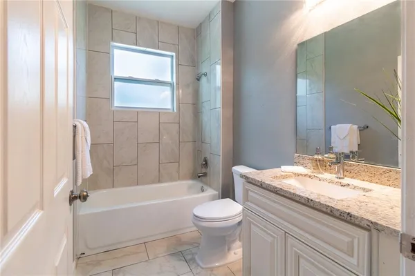 a bathroom with a granite countertop toilet a sink and a bathtub
