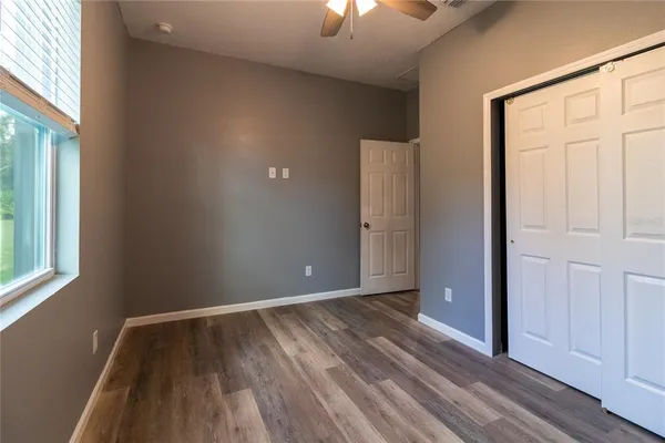 an empty room with wooden floor closet and windows