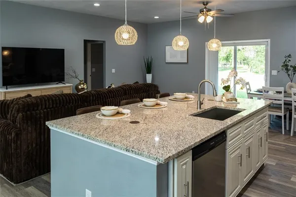 a kitchen with stainless steel appliances granite countertop a sink a stove and a wooden floor