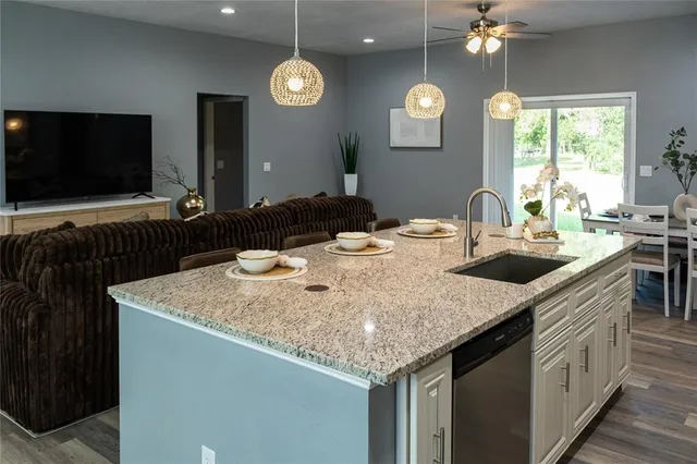 a kitchen with stainless steel appliances granite countertop a sink a stove and a wooden floor