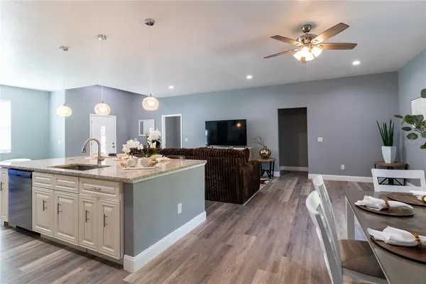 a view of a kitchen counter space a sink wooden floor and a view of living room