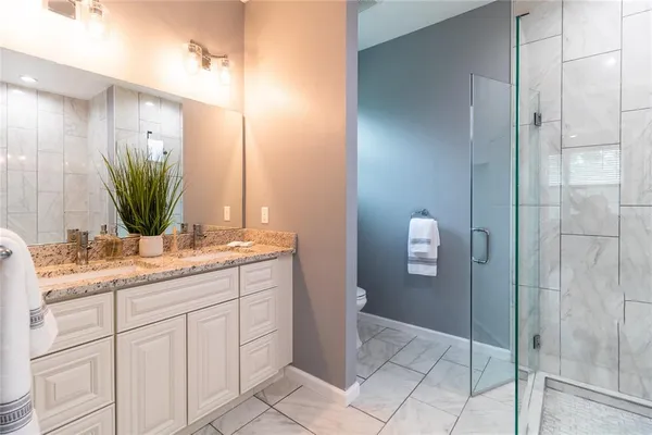 a bathroom with a granite countertop sink a mirror and a shower