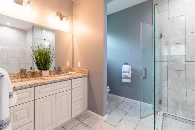 a bathroom with a granite countertop sink a mirror and a shower