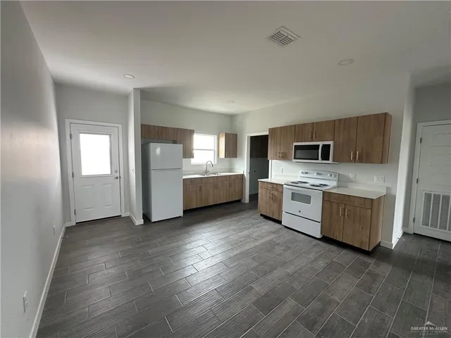 a view of a kitchen with a sink stove cabinets and empty room