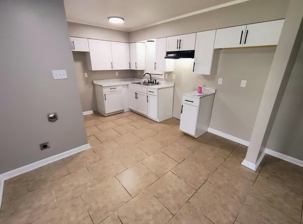a kitchen with a sink a stove a refrigerator and white cabinets