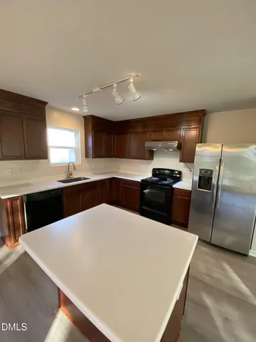 a kitchen with granite countertop a sink a counter space stainless steel appliances and cabinets