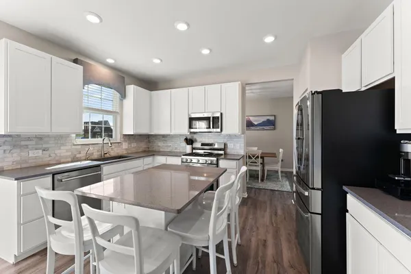 a kitchen with granite countertop a refrigerator stove microwave and cabinets