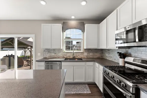a kitchen with stainless steel appliances granite countertop a stove a sink and a microwave