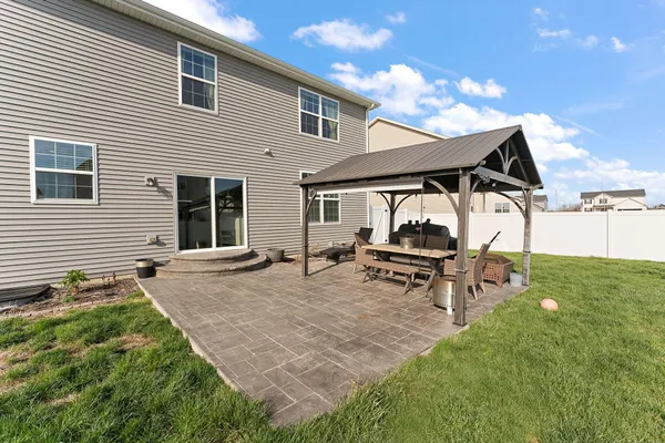 a backyard of a house with wooden table and chairs